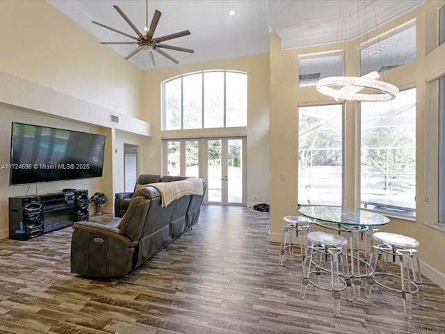 living room featuring ceiling fan, a high ceiling, dark hardwood / wood-style floors, and french doors