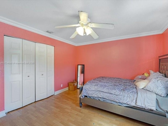 bedroom featuring light wood-type flooring, ceiling fan, crown molding, and a closet