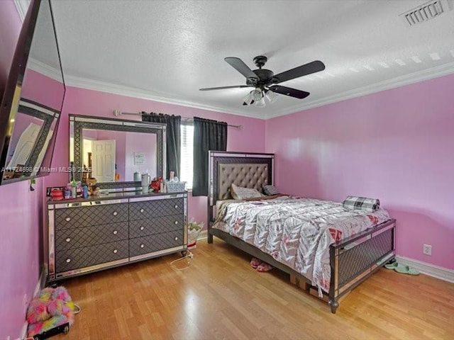 bedroom with a textured ceiling, ceiling fan, crown molding, and wood-type flooring