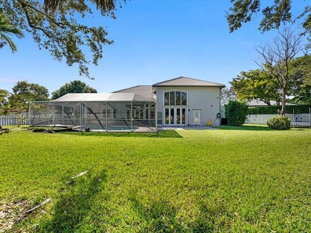 rear view of property featuring a lanai, a yard, french doors, and a fenced in pool