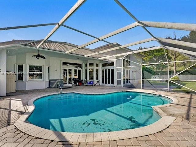 view of swimming pool featuring ceiling fan, glass enclosure, and a patio