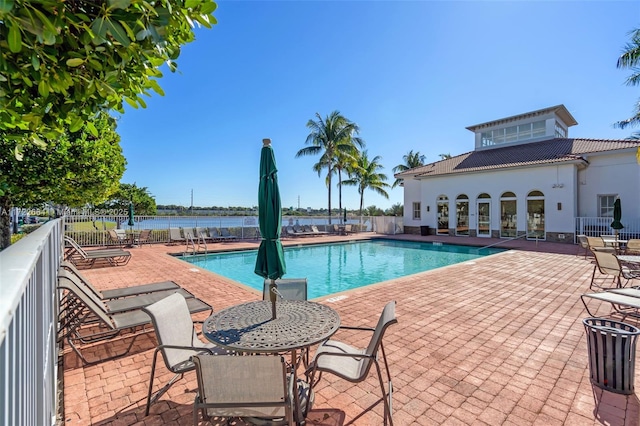 view of pool with a water view and a patio