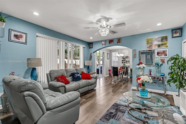 living room with ceiling fan with notable chandelier and hardwood / wood-style flooring