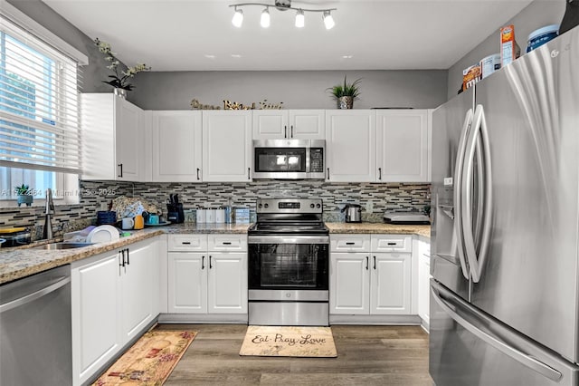 kitchen with white cabinetry, light stone countertops, dark hardwood / wood-style floors, and appliances with stainless steel finishes