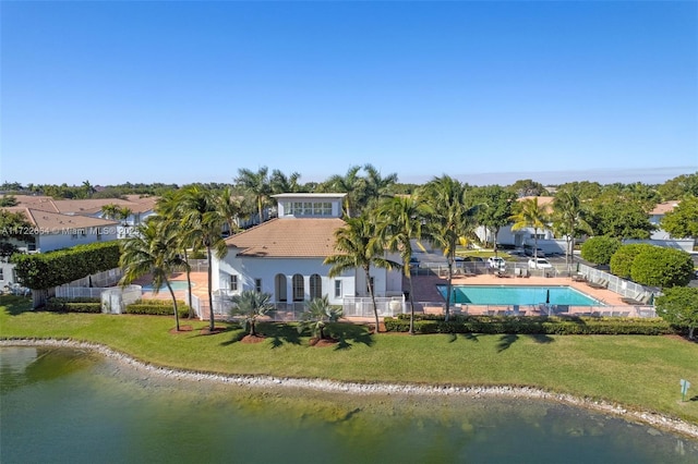 rear view of house with a lawn, a water view, and a fenced in pool