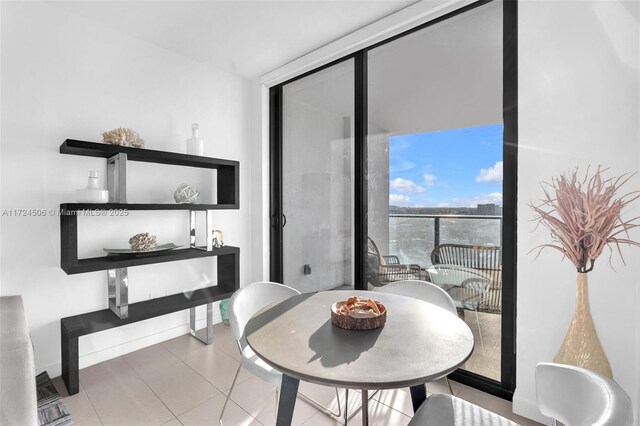 kitchen with a kitchen bar, stainless steel refrigerator, white cabinetry, and light tile patterned floors