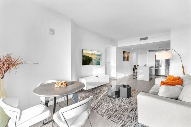 kitchen with appliances with stainless steel finishes, wall chimney exhaust hood, a breakfast bar, a center island, and white cabinetry