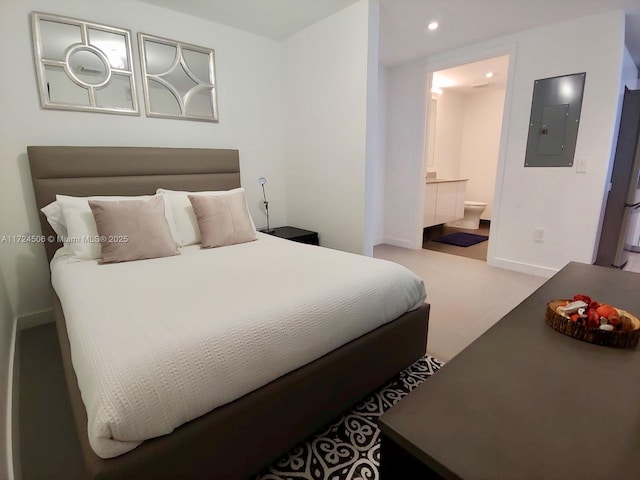 bedroom featuring connected bathroom, electric panel, and light colored carpet