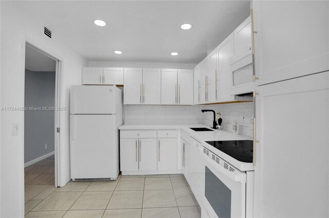 kitchen with white appliances, white cabinets, light tile patterned flooring, and sink