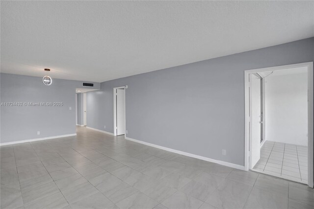 tiled empty room featuring a textured ceiling