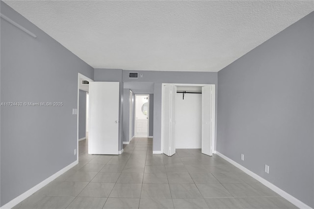 unfurnished bedroom featuring light tile patterned floors, a closet, a textured ceiling, and a barn door