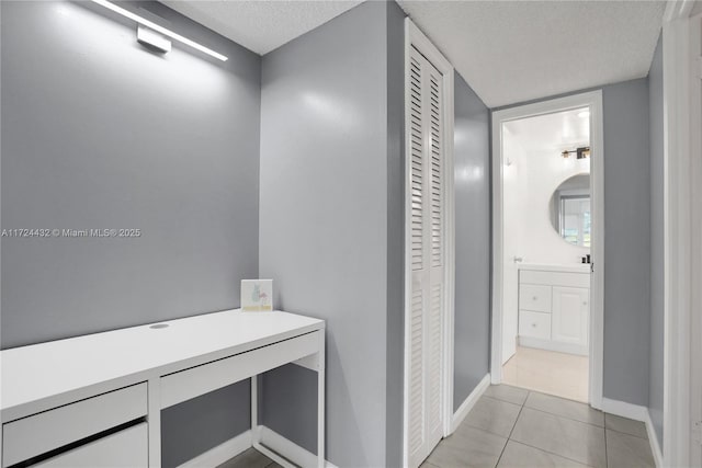 hall featuring light tile patterned floors and a textured ceiling