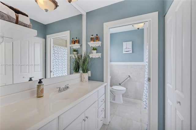 bathroom with vanity, tile patterned flooring, toilet, and tile walls