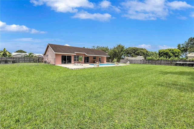 rear view of house featuring a yard, a fenced in pool, and a patio area