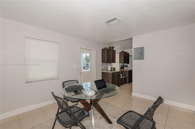 tiled dining room featuring electric panel and a textured ceiling