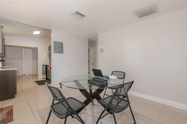 dining space featuring light tile patterned floors, a textured ceiling, and electric panel