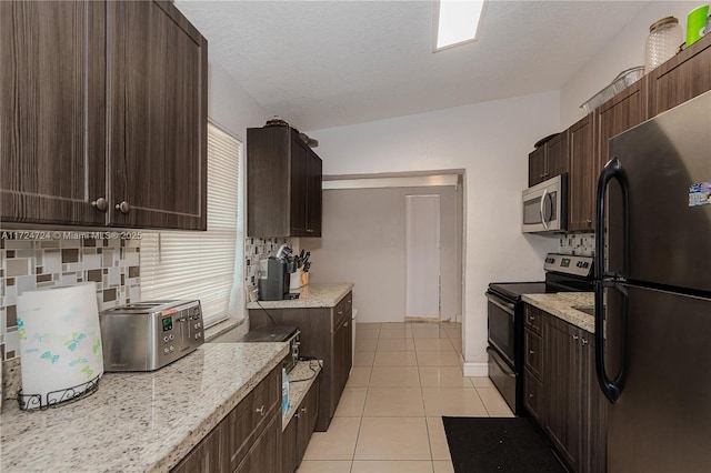 kitchen with light stone countertops, a textured ceiling, appliances with stainless steel finishes, dark brown cabinets, and light tile patterned flooring