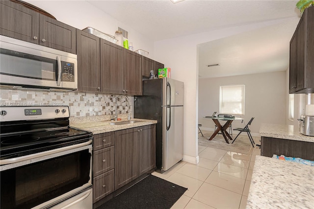 kitchen featuring decorative backsplash, appliances with stainless steel finishes, dark brown cabinetry, and sink