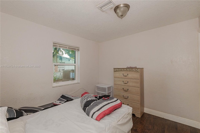 bedroom with a textured ceiling and dark hardwood / wood-style floors