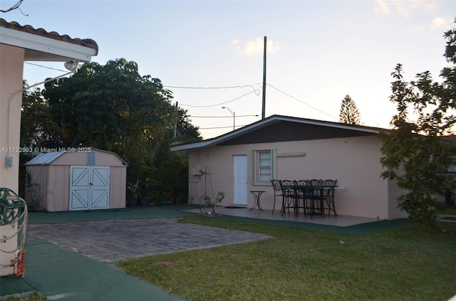 exterior space featuring a storage shed, a lawn, and a patio