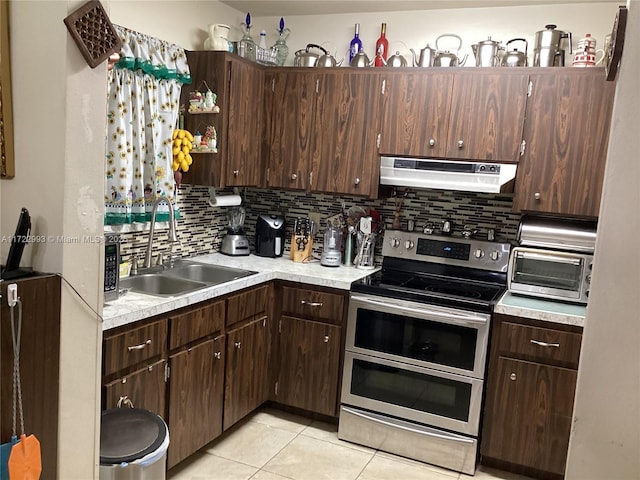 kitchen featuring sink, light tile patterned floors, dark brown cabinets, tasteful backsplash, and range with two ovens