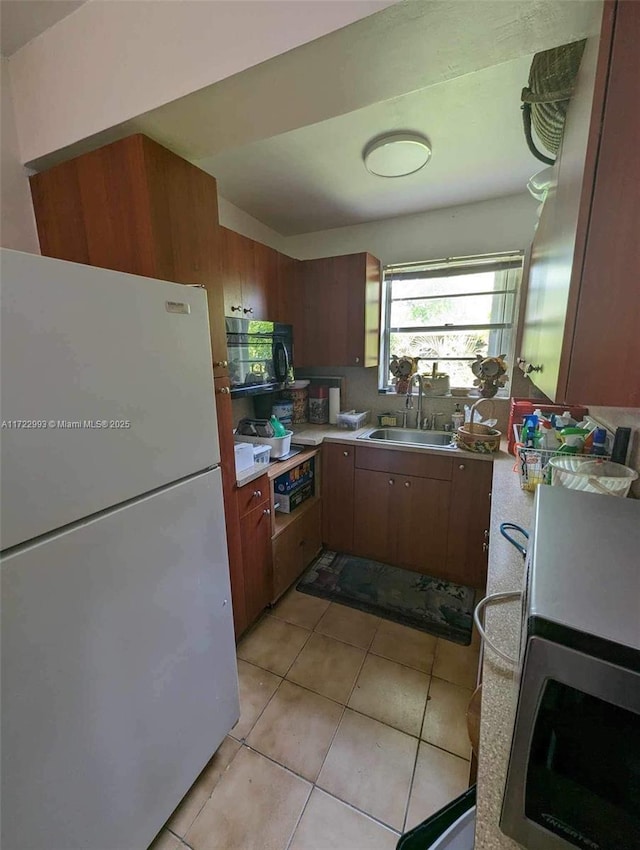 kitchen featuring white refrigerator, sink, and light tile patterned floors