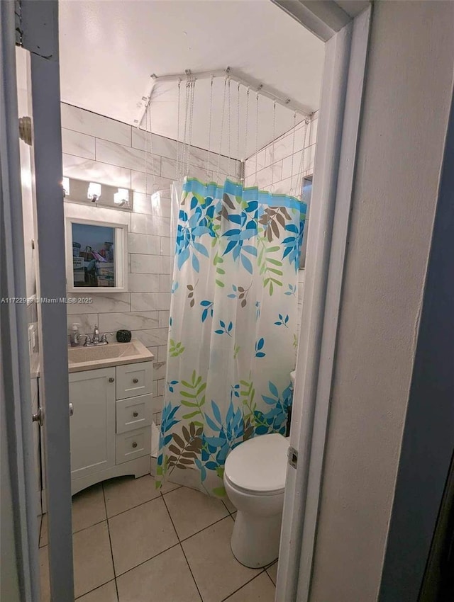 bathroom with tile walls, vanity, curtained shower, tile patterned floors, and toilet