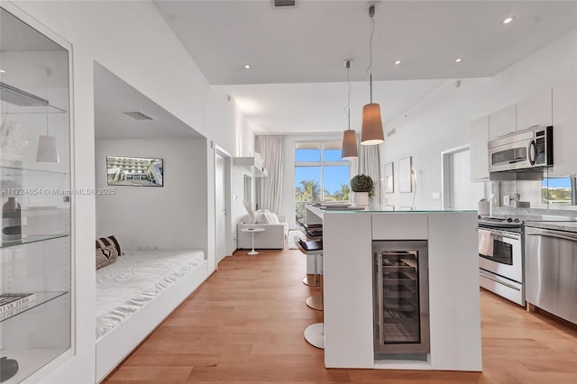 kitchen with white cabinetry, hanging light fixtures, beverage cooler, light hardwood / wood-style floors, and appliances with stainless steel finishes