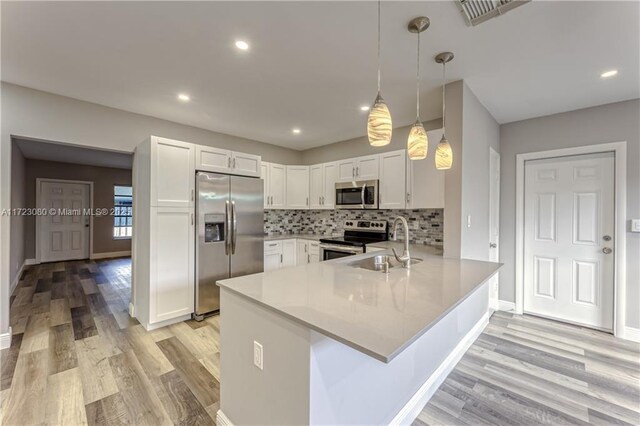 kitchen featuring decorative light fixtures, white cabinetry, appliances with stainless steel finishes, and kitchen peninsula