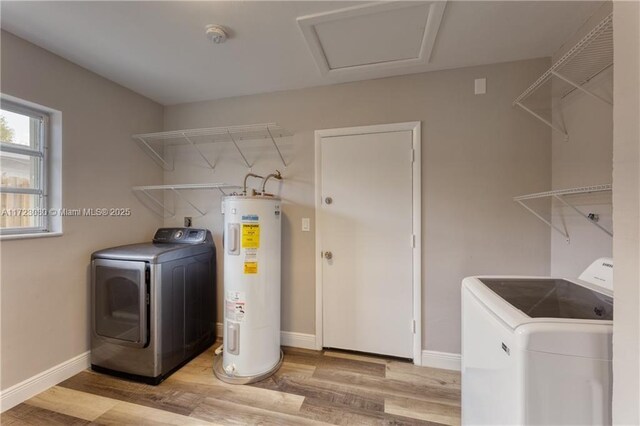 washroom with electric water heater, light wood-type flooring, and washing machine and clothes dryer