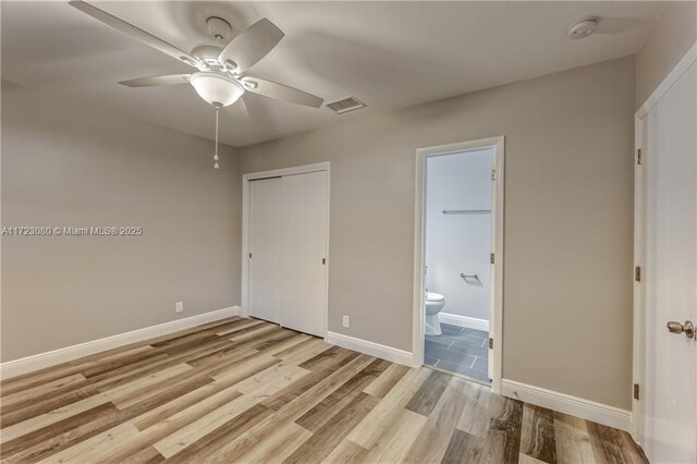 unfurnished bedroom featuring ceiling fan, a closet, connected bathroom, and light hardwood / wood-style floors