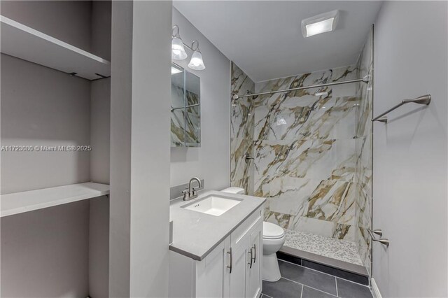 bathroom featuring toilet, vanity, tile patterned floors, and a tile shower