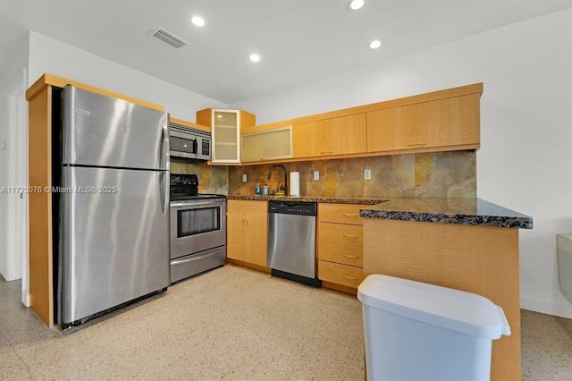 kitchen featuring sink, appliances with stainless steel finishes, dark stone counters, and tasteful backsplash