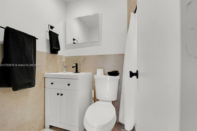 bathroom with toilet, vanity, and tile walls