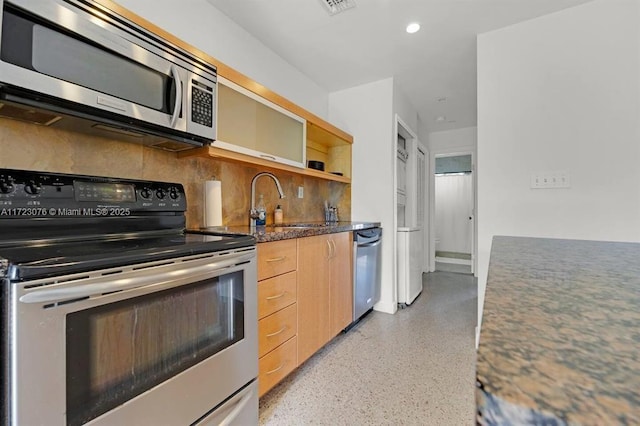 kitchen with decorative backsplash, sink, stainless steel appliances, light brown cabinetry, and dark stone counters