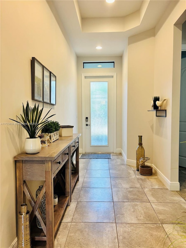 entryway with a raised ceiling and light tile patterned floors