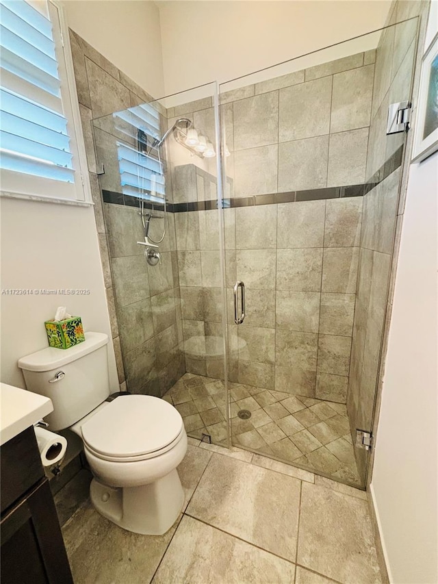 bathroom with vanity, a shower with shower door, and toilet