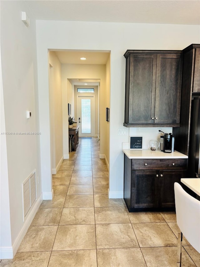 kitchen featuring black refrigerator, dark brown cabinets, and light tile patterned floors