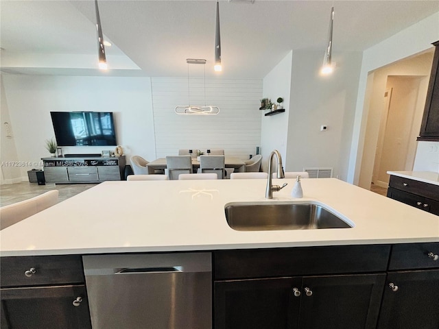 kitchen with sink, decorative light fixtures, stainless steel dishwasher, and an island with sink