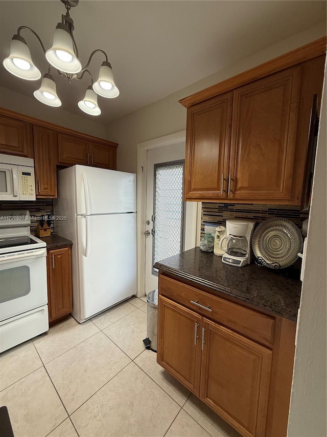 kitchen featuring light tile patterned flooring, white appliances, and hanging light fixtures