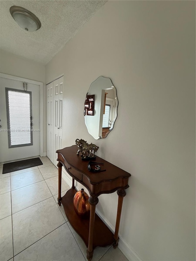 entryway with light tile patterned floors and a textured ceiling