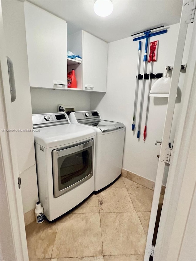 clothes washing area with washer and dryer, light tile patterned floors, and cabinets