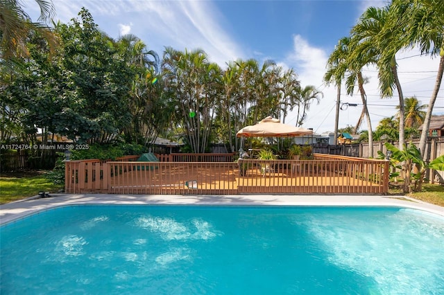 outdoor pool with a fenced backyard and a wooden deck