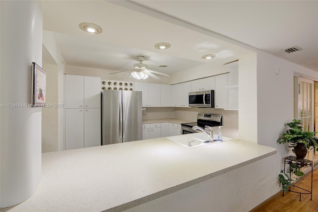 kitchen featuring stainless steel appliances, light countertops, a sink, and a peninsula