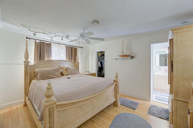 bedroom with light wood-style flooring, crown molding, visible vents, and a textured ceiling