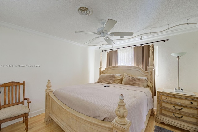 bedroom with a textured ceiling, ceiling fan, light wood-style flooring, visible vents, and crown molding