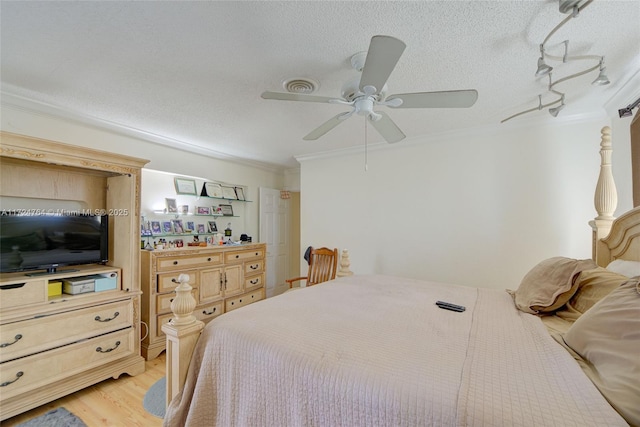 bedroom with light wood finished floors, visible vents, ceiling fan, crown molding, and a textured ceiling