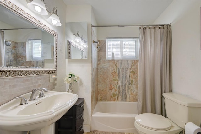 bathroom featuring tile walls, toilet, a sink, shower / bath combo with shower curtain, and backsplash