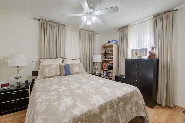 bedroom featuring a textured ceiling, light wood finished floors, and a ceiling fan