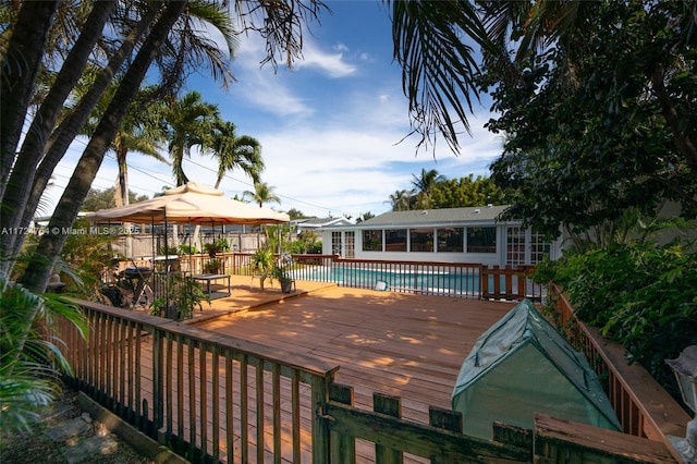 deck featuring a fenced in pool, a sunroom, and a gazebo